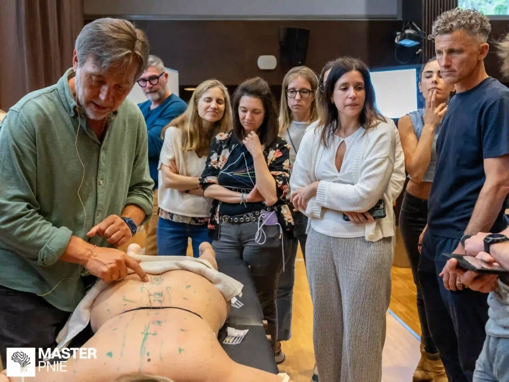 Sesión práctica del Máster en Psiconeuroinmunología en Barcelona, con alumnos observando una demostración clínica aplicada durante una formación presencial.