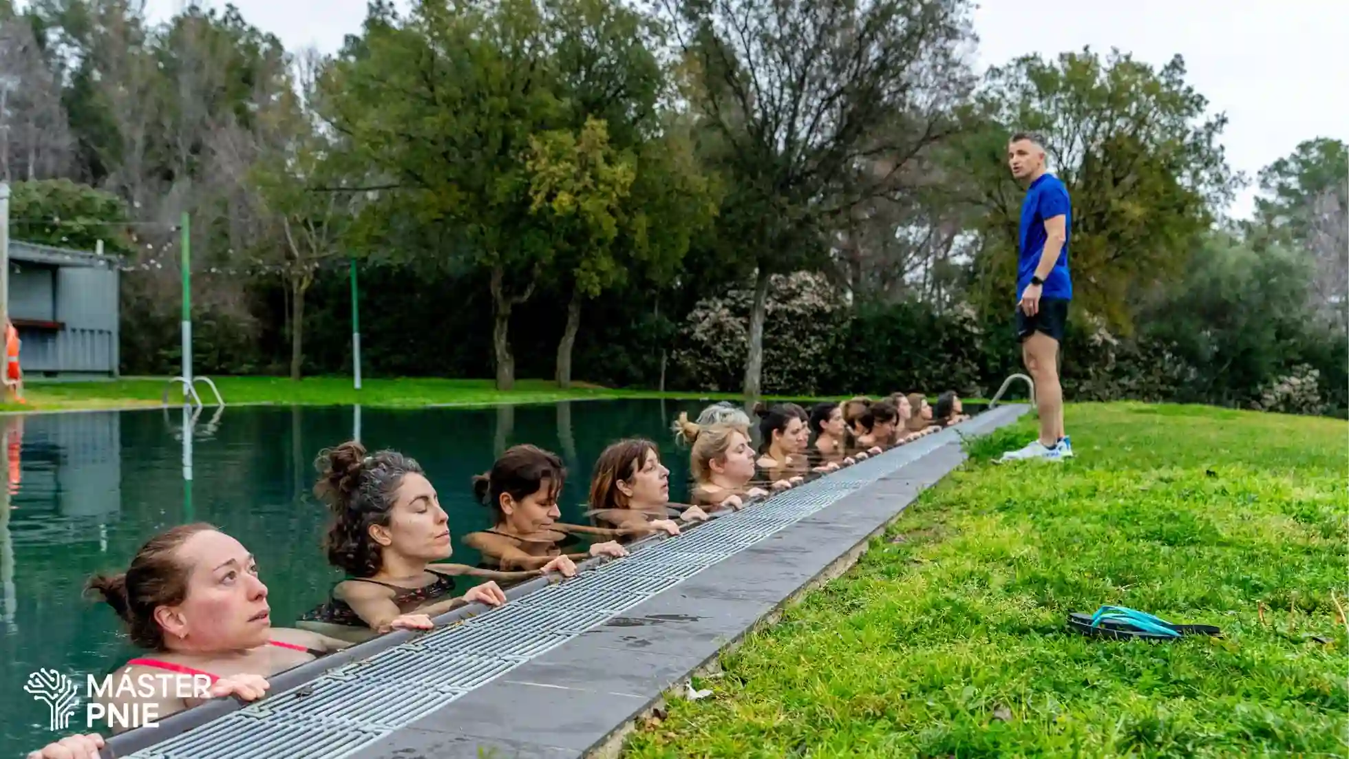 Varias personas en el borde de una piscina participando en una actividad acuática del Retiro Inaugural del Máster PNIE Xevi Verdaguer.