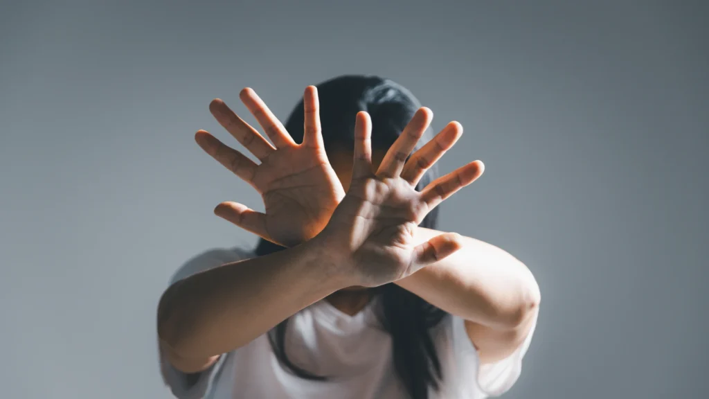 Persona cubriéndose el rostro con las manos como señal de rechazo o amenaza social, concepto de estrés social.
